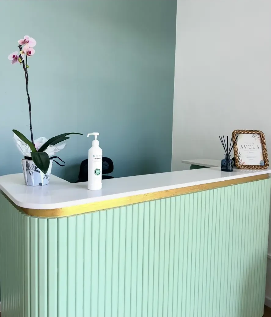 Reception desk at Avela Medical Practice, with the practice name on the wall behind it